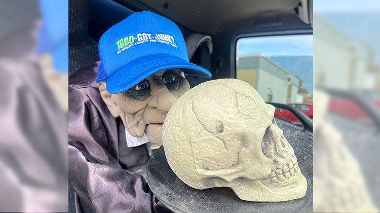 Skull on a platter Halloween ghoul wearing a 1-800-GOT-JUNK? hat, holding a skull on a platter