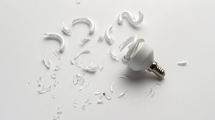 CFL bulb broke A broken CFL bulb with glass shards spread across white tabletop