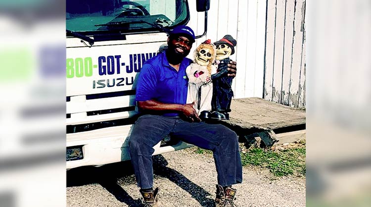 1-800-GOT-JUNK? team member holding two skeleton dolls wearing wedding attire 1-800-GOT-JUNK? team member holding two skeleton dolls wearing wedding attire