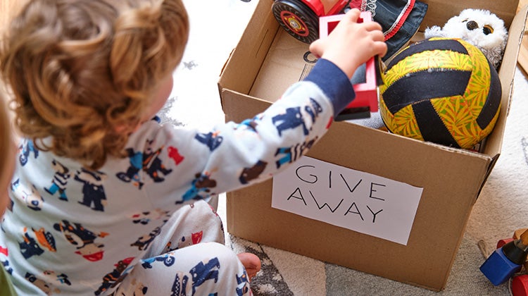 Spring cleaning for a fresher lighter you Child putting toys in box for donations