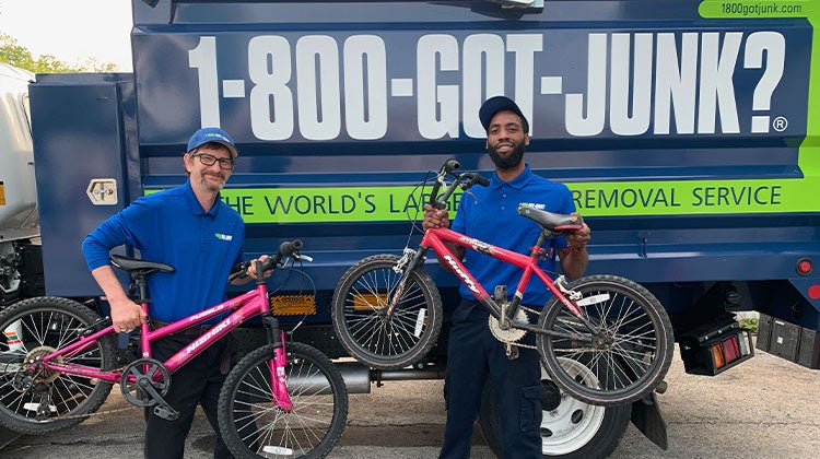 Two 1-800-GOT-JUNK? team members holding bikes Two 1-800-GOT-JUNK? team members holding bikes