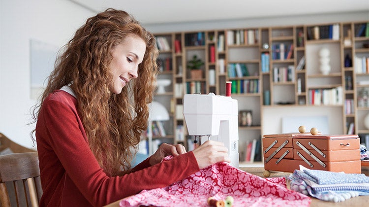Woman with curly red hair using a sewing machine Woman with curly red hair using a sewing machine
