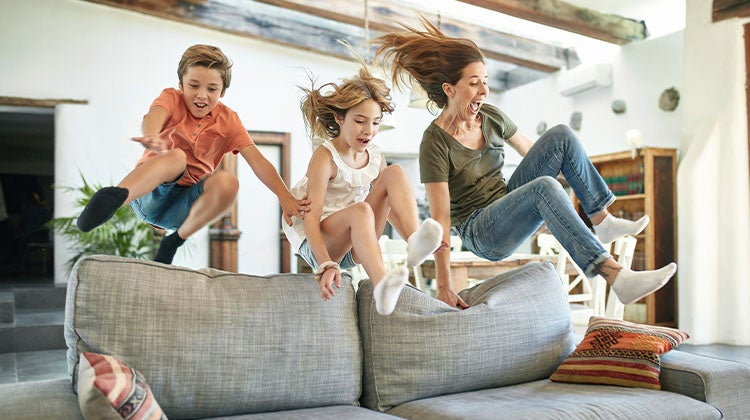 Mom and two kids jumping onto a couch Mom and two kids jumping onto a couch
