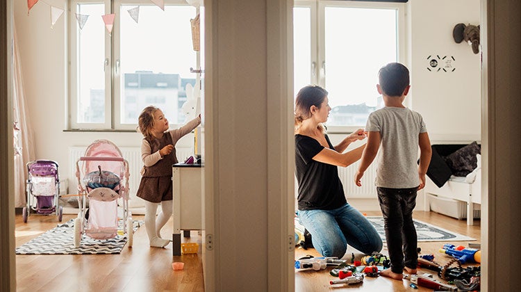 Mother and two children searching through toys to donate Mother and two children searching through toys to donate