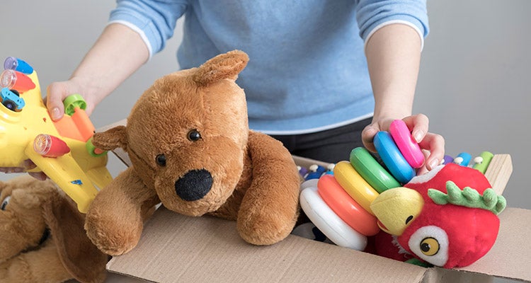 Person putting away old toys in a cardboard box Person putting away old toys in a cardboard box